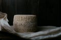 kravot cheese head on a background of dark wooden boards and parchment paper. homemade hard cheese circle in low key