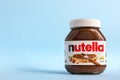 Nutella in a glass jar on a blue background.