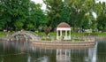 Kremenchuk city, Ukraine - July 26, 2022: A beautiful pond with a white gazebo on an island and an iron bridge