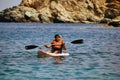 Kreta or Crete Greece - A man in life jacket floating on a kayak in a sea against blurred rocky mountain in the background. Water