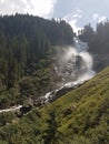 Krimml waterfall Austria rushing water with extreme power surrounded by tall green trees and blue bright sky Royalty Free Stock Photo