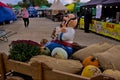 Funny figure of a colorful character, pumpkins and autumn flowers at an outdoor fair.