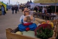 Funny figure of a colorful character, pumpkins and autumn flowers at an outdoor fair.