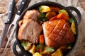 Krustenbraten Pork Roast with Crispy Rind with vegetables close-up in a frying pan. horizontal top view