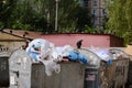 Trash in overloaded garbage bins in courtyard of residential district