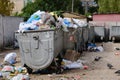 Trash in overloaded garbage bins in courtyard of residential district