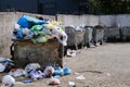 Trash in overloaded garbage bins in courtyard of residential district