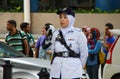 Asian police woman stands along the road in a white uniform, cap and hijab