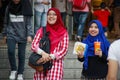 Two young girls in bright hijabs are walking and laughing near the Petronas Towers