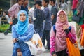 Two young girls in bright hijabs are walking and laughing near the Petronas Towers