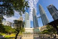 Kuala Lumpur, Malaysia - August 13, 2022: View of the Twin Towers through the palm trees of KLCC Park. Urban oasis with water