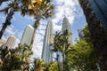 Kuala Lumpur, Malaysia - August 13, 2022: View of the Twin Towers through the palm trees of KLCC Park. Urban oasis with water