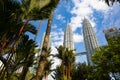 Kuala Lumpur, Malaysia - August 13, 2022: View of the Twin Towers through the palm trees of KLCC Park. Urban oasis with water