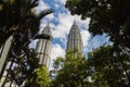 Kuala Lumpur, Malaysia - August 13, 2022: View of the Twin Towers through the palm trees of KLCC Park. Urban oasis with water