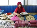 A woman fills a plate with dried fish at Chow Kit Market in Kuala Lumpur