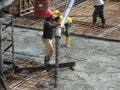 Construction workers pouring wet concrete using concrete spider hose