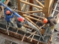 Construction workers pouring wet concrete using concrete spider hose
