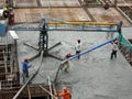 Construction workers pouring wet concrete using concrete spider hose