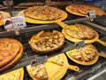 Hot pizzas displayed on the rack for sale inside glass warmer in the shopping mall.