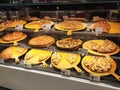 Hot pizzas displayed on the rack for sale inside glass warmer in the shopping mall.