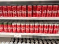 Soft drinks in cans are displayed on a shelf for sale in a large supermarket.