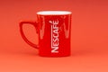 Red Nescafe mug isolate on red background.