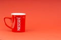 Red Nescafe mug isolate on red background.