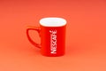 Red Nescafe mug isolate on red background.