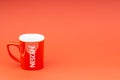 Red Nescafe mug isolate on red background.