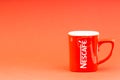 Red Nescafe mug isolate on red background.