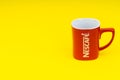 Red Nescafe mug isolate on yellow background