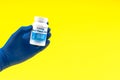 Hand in a blue glove holding multivitamin bottle Royalty Free Stock Photo