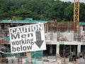 Safety signage `CAUTION - Men Working Below` at the construction site.