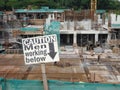 Safety signage `CAUTION - Men Working Below` at the construction site.