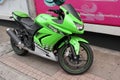 A green Kawasaki Ninja motor bike parked on a pavement in the city