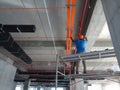 Construction workers installing electrical cable tray on the floor soffit.