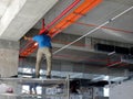 Construction workers installing electrical cable tray on the floor soffit.