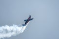 Silhouette of an airplane with trail of smoke behind against background of blue sky.