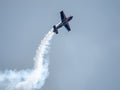 Silhouette of an airplane with trail of smoke behind against background of blue sky. Royalty Free Stock Photo