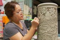 Woman cuts traditional tribal tattoo motives decoration at the raw kaolin in a workshop in Kuching, Malaysia.