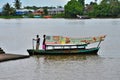 Weathered boat with sailor & passenger and solar panel crosses Sarawak River Kuching Malaysia