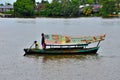 Weathered boat with sailor & passenger and solar panel crosses Sarawak River Kuching Malaysia