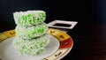 Three Kuih Lopes on a round plate with fork, syrup on the side, wooden table.