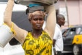 Unidentified Ghanaian woman carries a basin on her head and a b