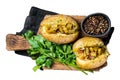 Kumpir, baked Jacket potatoes stuffed with cheese, bacon, salty cucumber, herbs and butter. Isolated, white background.