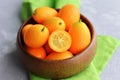 Kumquat fruits in wooden bowl on linen napkin background. Healthy vegetarian food. Kumquat fruit cut in half. Royalty Free Stock Photo