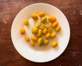 Kumquat fruit in white plate on a wooden background