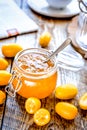 Kumquat on plate and jam in jar at wooden table