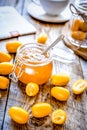 Kumquat on plate and jam in jar at wooden table