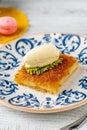 Kunefe with pistachios and ice cream on a porcelain plate on a wooden table Royalty Free Stock Photo